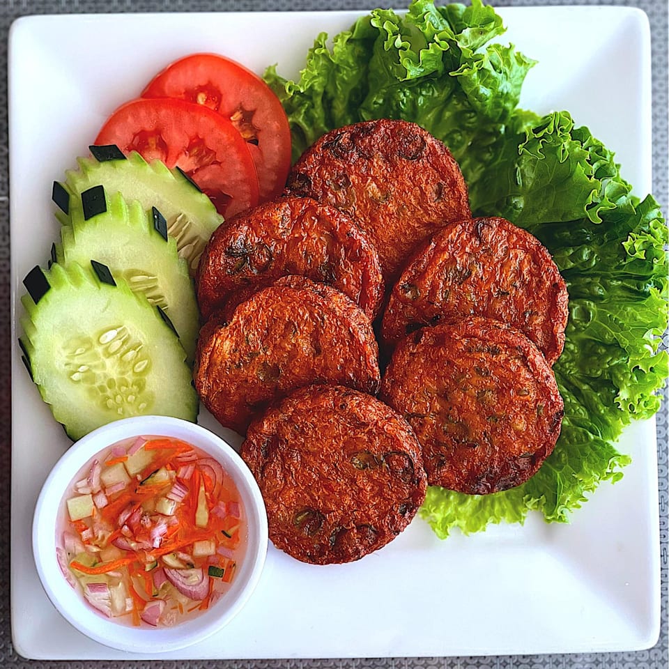U-D Thai Restaurant's fried fish cakes with lettuce, cucumber, tomato, and a side of dipping sauce.