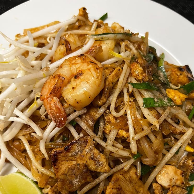 Close-up of U-D Thai Restaurant's Pad Thai with shrimp, chicken, bean sprouts, and lime.