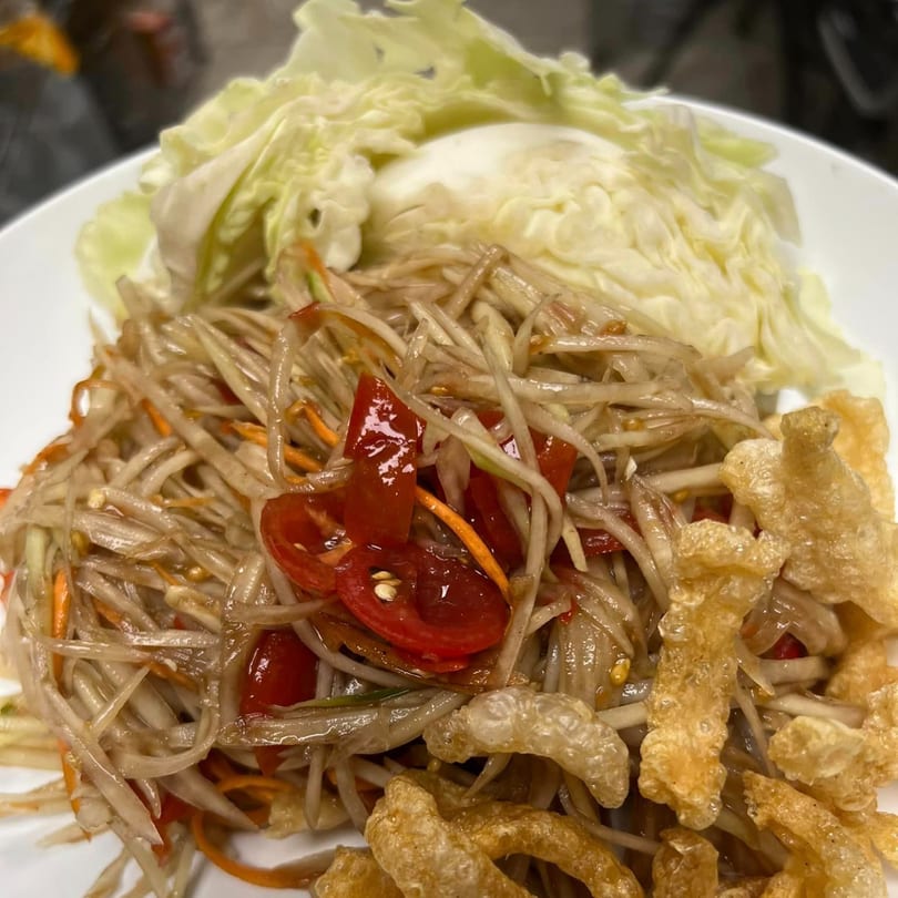 Close-up of U-D Thai Restaurant's papaya salad with tomatoes, cabbage, and crispy pork rinds.