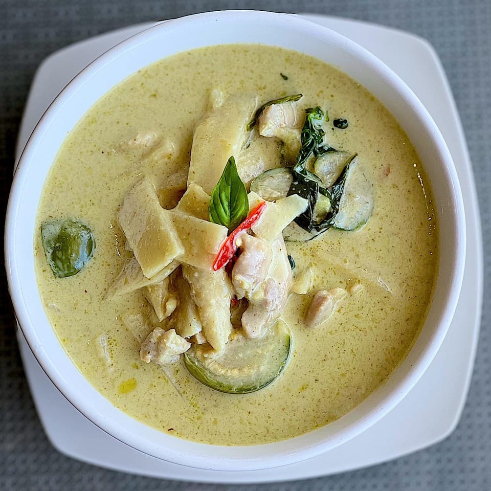U-D Thai Restaurant's green curry with chicken, bamboo shoots, and basil in a white bowl.